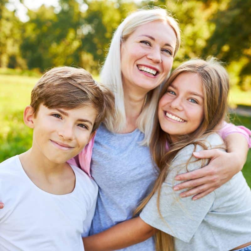 mom preteen son daughter outdoors yard smiles together happy