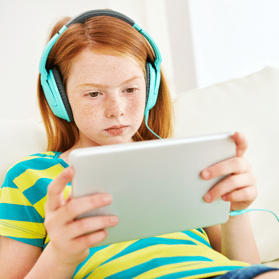 Screen time guidelines for children 3 Kid with blue headphones, playing on an ipad, representing screen time